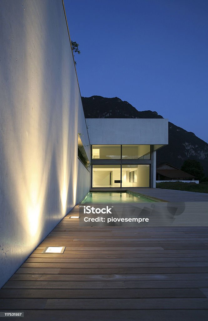 Highlighted white wall with wooden deck leading to house modern house http://i705.photobucket.com/albums/ww51/piovesempre/banner_Zanolari2.jpg http://i705.photobucket.com/albums/ww51/piovesempre/banner_architecture2.jpg Architecture Stock Photo