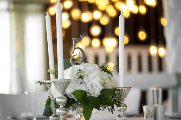 istock Wedding table setting is decorated with fresh flowers and white candles. Wedding floristry. Bouquet with roses, hydrangea and eustoma. On the background blur are burning garlands with light bulbs 1175315820
