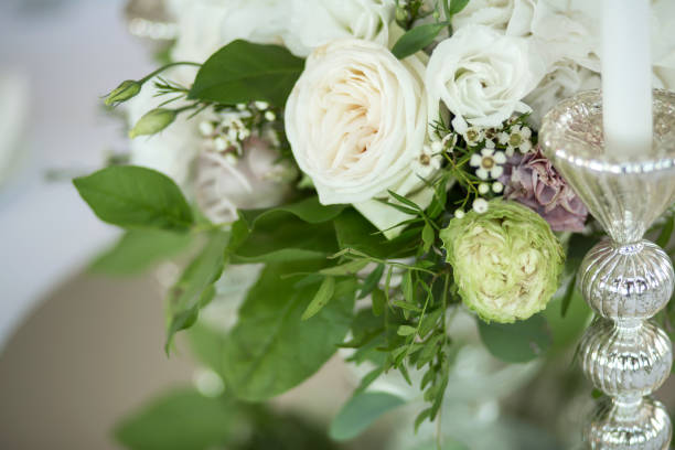 istock Wedding table setting is decorated with fresh flowers and white candles. Wedding floristry. Bouquet with roses, hydrangea and eustoma. Table numbering. 1175315893