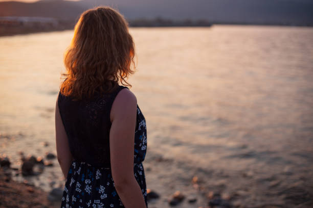 istock Young woman enjoying sunset on a beach 1175316688