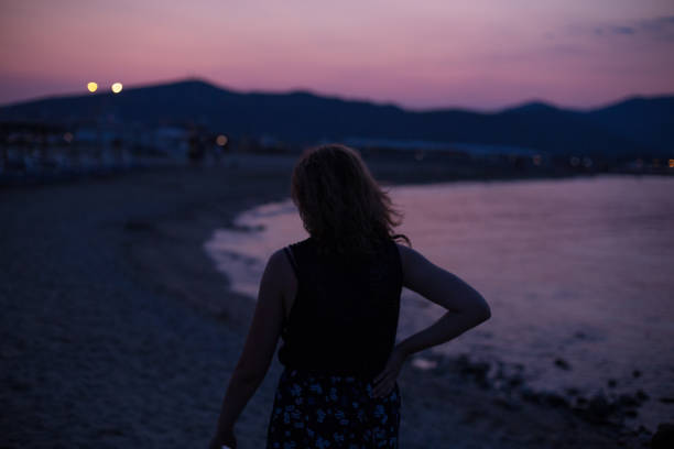 istock Young woman enjoying sunset on a beach 1175319039