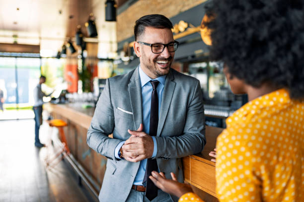 I just know we'll do great business together Happy Male and black female Business people having a conversation after work while standing in the beautiful restaurant during the day. business lunch stock pictures, royalty-free photos & images