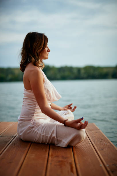 istock Woman meditating near water. 1175320660