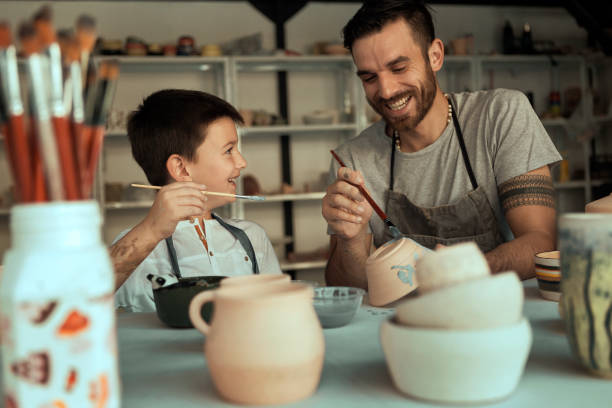istock Father painting pottery with son 1175323419