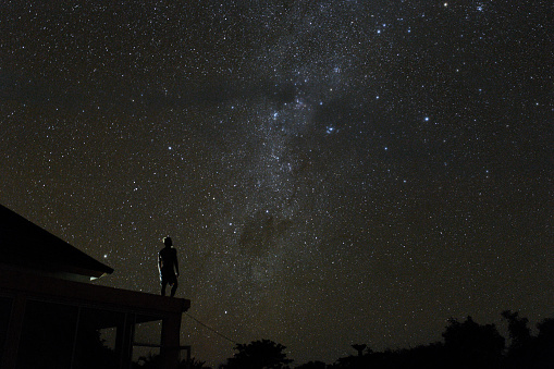 alone woman on rooftop watching mliky way and stars in the night sky on Bali island