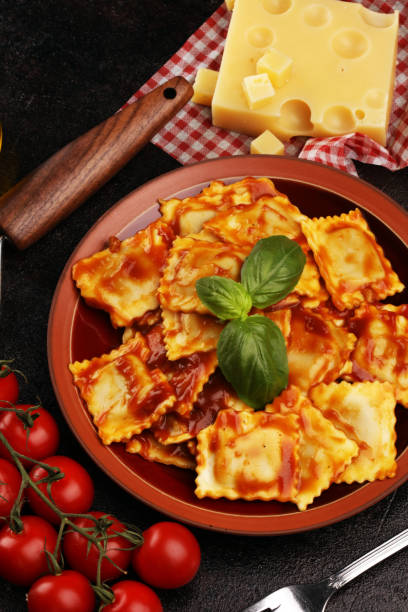istock Ravioli with tomato sauce garnished with parmesan cheese and basil on rustic table 1175340676