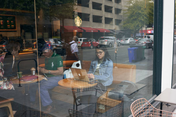 Portland, Oregon, USA - Sep 13, 2019: A young woman contemplates on her MacBook while sitting by the window in a Starbucks Coffee shop in downtown Portland.