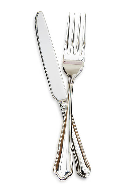 silver fork sitting across a silver knife - bestek stockfoto's en -beelden