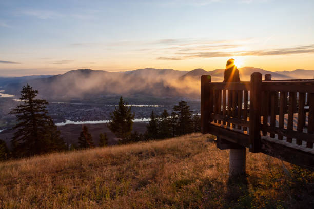 Kamloops Sunrise Girl Standing on a Lookout and looking at a Beautiful View of a Canadian City, Kamloops, during a colorful summer sunrise. Located in the Interior British Columbia, Canada. kamloops stock pictures, royalty-free photos & images