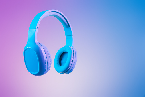 Elegantes auriculares azules en iluminación de fondo multicolor / duo tono photo