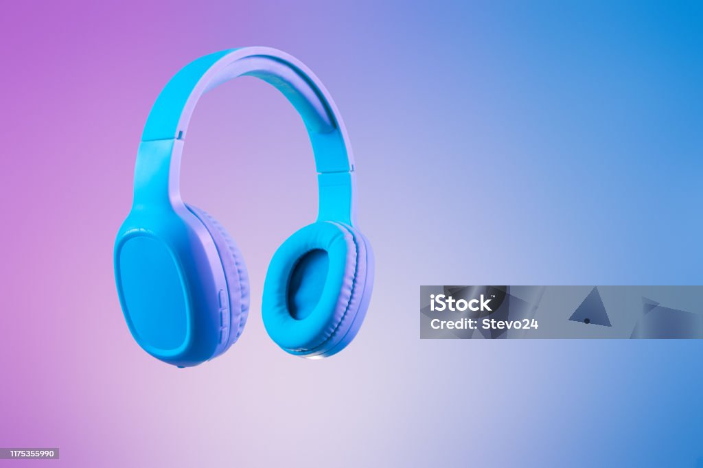 Stylish blue headphones on multi colored / duo tone background lighting Stylish blue headphones on multi colored / duo tone background lighting - lifestyle and fashion object concept image. Headphones Stock Photo