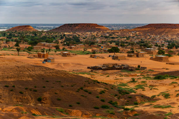 Traditional sahelian mudbrick village with mosque at the foothill of flat-topped hills viewed from a higher plateau with refresehd vegetation during summer rainy season outside Niamey capital of Niger Wide angle and telephoto lenses sahel stock pictures, royalty-free photos & images