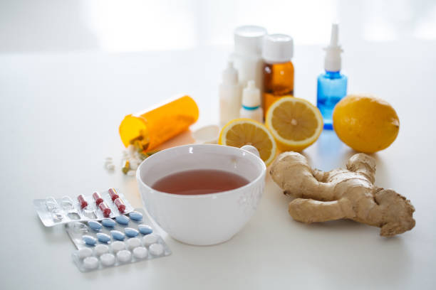 natural remedies mixed with pills and prescription medication - ginger tea cup cold and flu tea imagens e fotografias de stock