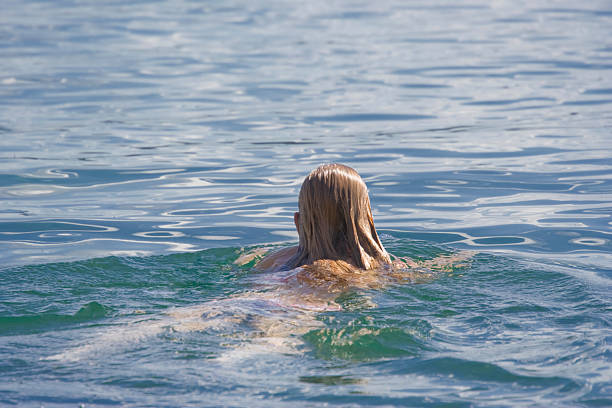 Blond girl looking blue Mediterranean sea as a tourist in Spain rear back view