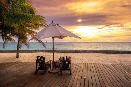 Umbrella and deck chairs on the beautiful tropical beach and sea at sunset time for travel and vacation