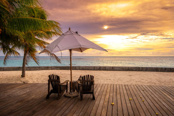 Umbrella and deck chairs on the beautiful tropical beach and sea at sunset time for travel and vacation stock photo
