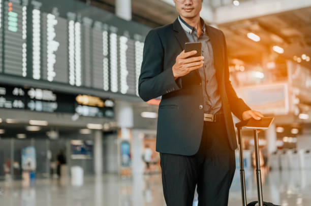 Young businessman at timetable screen board using smart phone.Flight board. stock photo