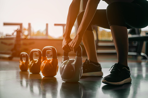 Mujer en equipo de ejercicio de pie en una fila sosteniendo mancuernas durante una clase de ejercicio en el gimnasio. Entrenamiento físico con kettlebell en gimnasio deportivo. photo