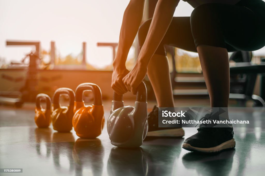 Woman in exercise gear standing in a row holding dumbbells during an exercise class at the gym.Fitness training with kettlebell in sport gym. Kettlebell Stock Photo