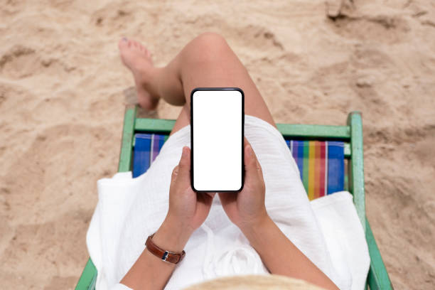istock a woman holding black mobile phone with blank desktop screen while lying down on a beach chair 1175381070