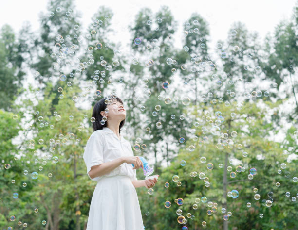 istock woman playing with soap bubbles machine 1175381910
