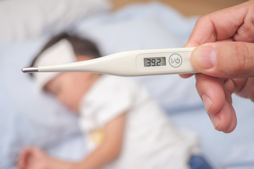 Fiebre, Termómetro médico de primer plano, Padre / Padre que mide la temperatura de su hijo enfermo, Asiático 3 - 4 años de edad niño pequeño tiene fiebre alta photo