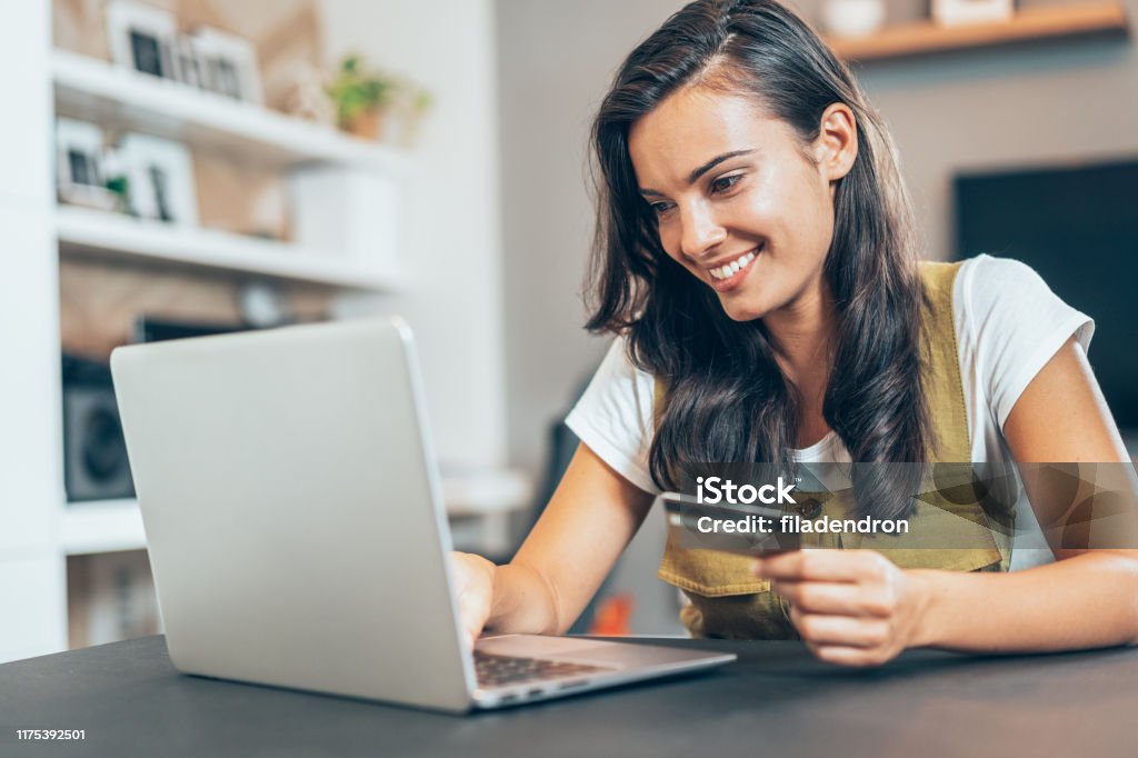 Online payment Young beautiful woman using credit card and laptop at home Playing Card Stock Photo