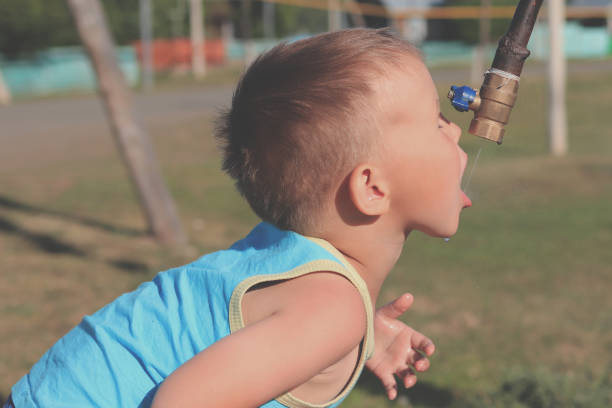 istock Child drinking water from tap outdoors. Water scarcity concept 1175396445
