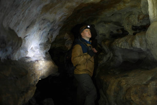 istock Man stands and looks up in a karst cave 1175397416