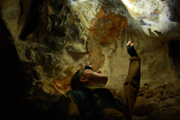 istock Man stands and pulls his hand up in a karst cave 1175397444