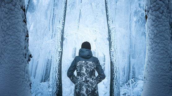 Woman walking through mysterious forest covered with fresh snow and ice crystals.