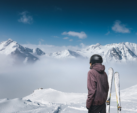 Skier enjoying the view on the top of the mountain. This image is a composite.