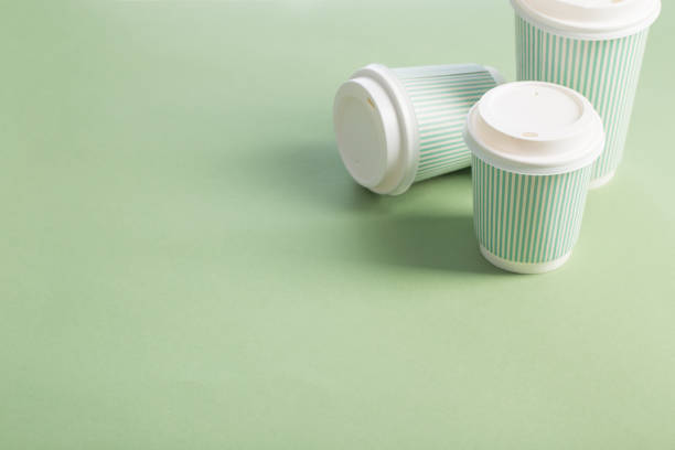 disposable paper cup with coffee on green background