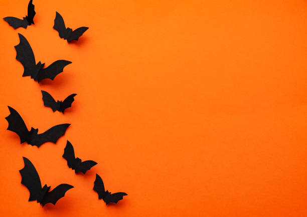 Halloween holiday decorations halloween  concept - black paper bats flying over orange background vampire photos stock pictures, royalty-free photos & images
