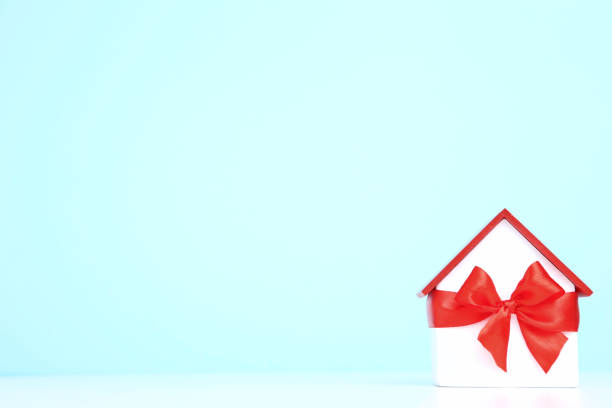 istock Wooden house model with ribbon bow on blue background 1175404601