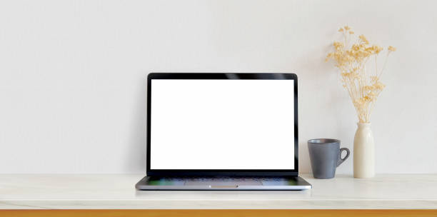 istock Open blank screen laptop computer on white wooden table in white minimal workplace 1175404656