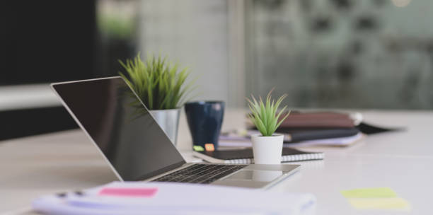 istock Open laptop with office supplies and documents on white table in modern office style 1175404676