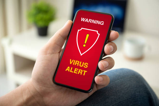 istock male hand holding phone with warning virus alert alarm 1175405704