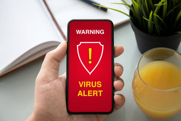 istock male hand holding phone with warning virus alert alarm 1175405740