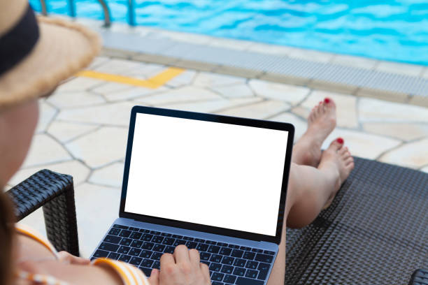 istock Young woman using laptop near a swimming pool 1175406674