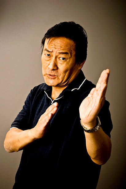 Studio shot of young Chinese man wearing traditional clothes against gray background