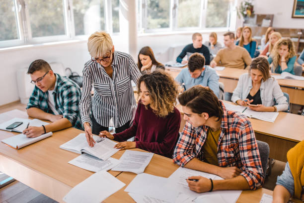 istock Senior professor assisting her students on a class at lecture hall. 1175414210