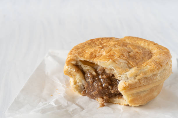 Mince Pie on Table Horizontal Close Up of  a Take Away Mince Pie on a White Table with Copy Space Horizontal meat pie stock pictures, royalty-free photos & images