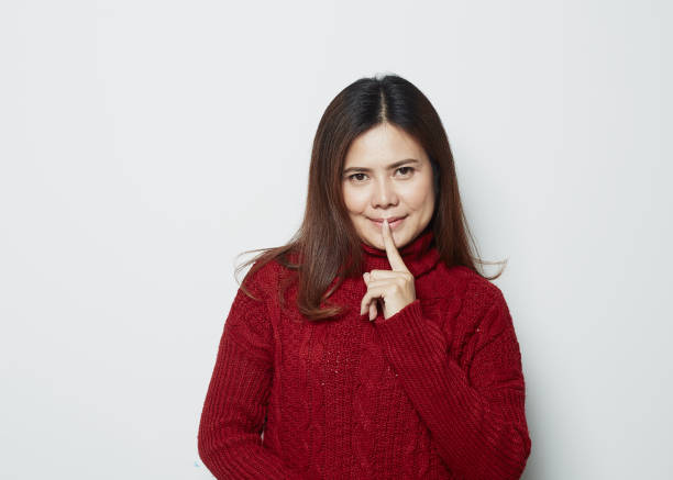 istock Asian woman doing silence gesture on studio background 1175415478
