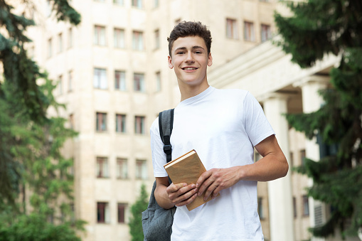 Excited student having break between classes near university, smiling to camera outdoors