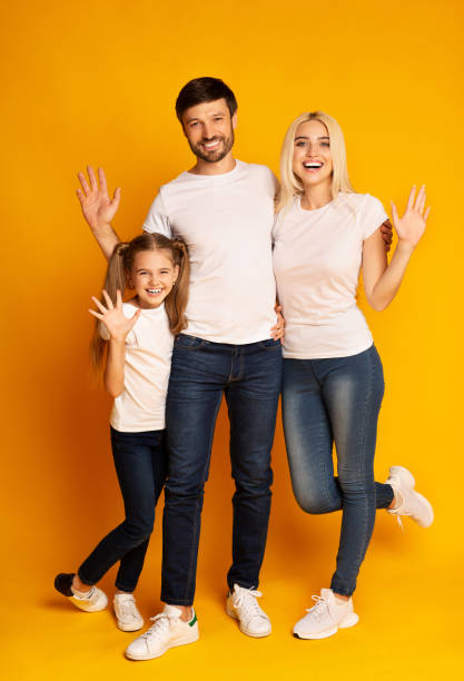 istock Happy Family Waving Hands Over Yellow Background 1175416532