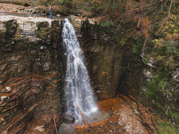 istock man standing on the cliff looking at waterfall autumn time 1175416540