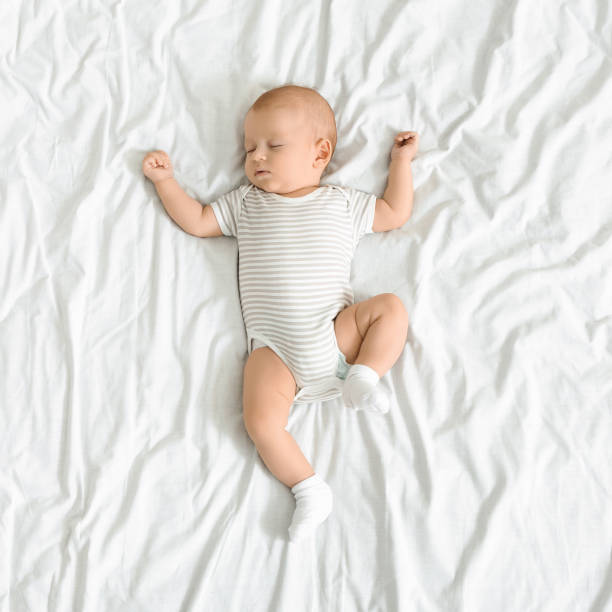 adorable bebé recién nacido siesta en manta blanca con los brazos en alto - sleeping baby fotografías e imágenes de stock