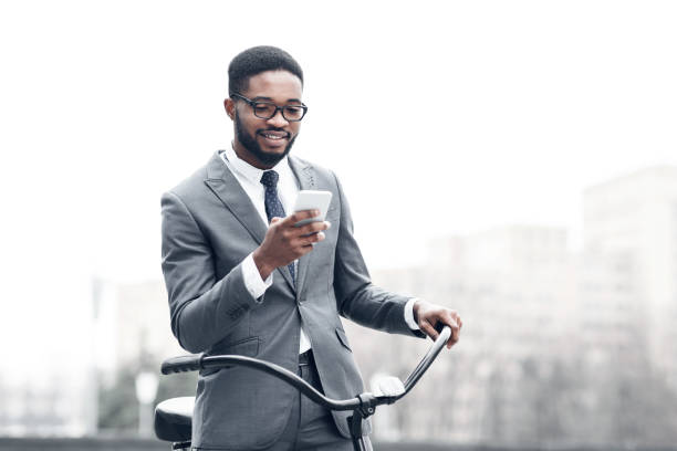 istock Afro businessman texting on phone, standing with bicycle 1175416863