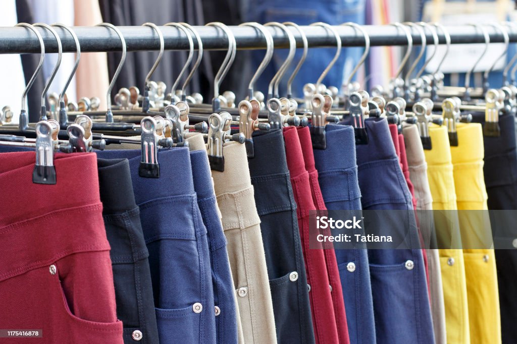 Multicolored casual pants hanging on hanger close up, side view Multicolored casual pants hanging on a hanger close up, side view Coathanger Stock Photo